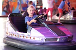 Happy teenager boy rides electric car during fan-fair entertainment