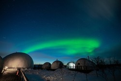 Northern Lights also known as aurora, borealis or polar lights at cold night over igloo village. Beautiful night photo of magic nature of winter landscape