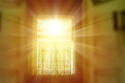 The bright rays of the sun illuminate the room through the old window of the village house.