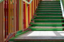 concrete staircase with green steps and multi-colored railing