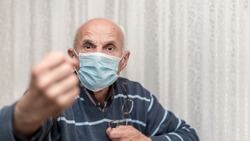 angry aggressive elderly man wearing face mask showing big fist self isolation and coronavirus concept white background