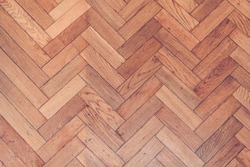 Parquet wooden old scratched floor with herringbone pattern view from top