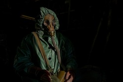Portrait of worker wearing green anti radiation costume and gas mask against black background