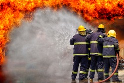 Fireman,fireman using water and extinguisher to fighting with fire flame in an emergency situation., under danger situation all firemen wearing fire fighter suit for safety. 