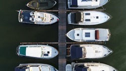 Aerial top down picture of marina a dock basin with moorings and supplies for yachts and small boats showing the floating dock walkway supported by pontoons and the recreational motor boats