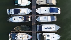 Aerial top down photo of marina a dock basin with moorings and supplies for yachts and small boats showing the floating dock walkway supported by pontoons and the recreational motor boats