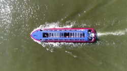 Aerial top down photo of electric canal cruise boat with sliding panel glass roof moving over IJ this is one of most popular tourist activities done in Amsterdam Netherlands