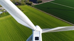 Aerial close up photo of wind turbine providing sustainable energy by spinning blades the power also known as renewable is collected from resources green field meadow in background