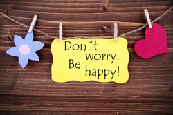 Yellow  Label Don't Worry Be Happy On Wooden Background With Two Symbols Like Heart And Flower