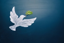Dove of peace concept. Symbol of freedom and international day of peace. Chalk painted dove with olive branch