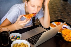 Woman works at the computer and eating fast food. Unhealthy Lifestyle