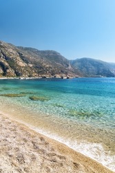 View of wonderful clear water of the Mediterranean Sea from Oludeniz Beach in Turkey. Scenic mountains are visible in background. Oludeniz is a popular tourist attraction in Turkey.