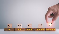 customer services best excellent business rating experience. Satisfaction survey concept. Hand of a businessman chooses a smiley face on wood block cube. 5 Star Satisfaction.