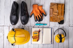 Workwear for a production worker on a white table. Personal protection accessories and electric tools used at work. Light background.