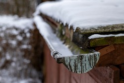 A snow-covered gutter on the roof. Snow lying on the roof and gutter for drainage. Winter season