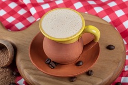 Traditional Turkish Dibek coffee in coffee cup on wooden table. Turkish dibek coffee grinded in a large stone mortar with the traditional hand beating method.