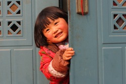 Cute kid hiding behind the door and peeking