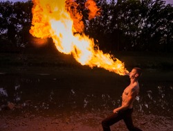  Man fire-eater blowing a large flame from his mouth