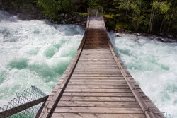 Wooden bridge over a rushing, rolling river on the  trail through Buerdalen to Buer glacier, Folgefonna national park, Norway, Europe