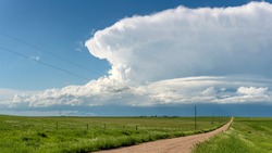 Panorama of a massive storm system, which is a pre-tornado stage, passes over a grassy part of the Great Plains while fiercely trying to generate more energy.