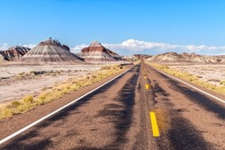 The remote roadway deep in the heart of the Petrified Forest National Park shows the beautiful mountain scenery of the painted desert during the scenic drive . 