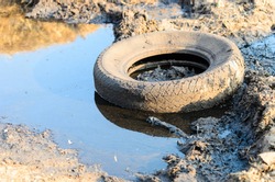 A discarded old tyre in a puddle of contaminated water