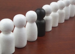 Row of white people figures with one black figure on wooden background.
