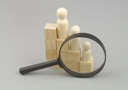 Career review concept. Wooden people figures as employers on stair under magnifying glass.