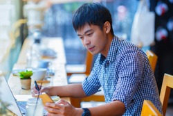asian man looking to a smart phone in coffee shop