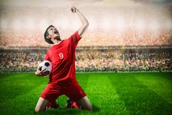 striker soccer football player in red team concept celebrating goal in the stadium during match


