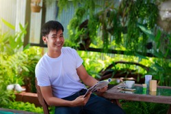 smiling asian casual man reading magazine 