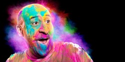 Bald cheerful man with colored face celebrating holi color festival. Man having fun with colorful powder. Portrait with copy space for your text