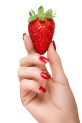 Close up female hand with pretty manicured nails with red nail varnish holding a luscious ripe strawberry in matching color tone in a healthy clean eating diet concept, isolated on white background
