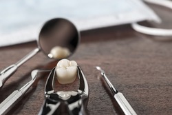 Tooth extraction concept with an array of stainless steel dental tools and a mask with the extracted tooth clasped in the pincers and reflected in the mirror