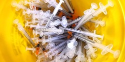close up of the used vaccine needles in the sharp bin. 