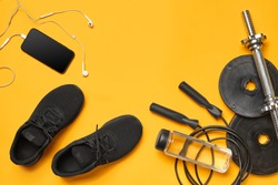 Close-up studio shot of a gym accessories on a yellow background. Top view, flat lay.