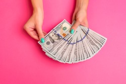 A woman is holding money in her hands. Pink background. Top view copy space.
