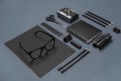 A set of black office accessories, glasses and old camera on gray background
