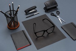 A set of black office accessories, glasses on gray background