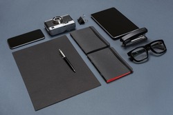 A set of black office accessories, glasses, old camera and tablet on gray background
