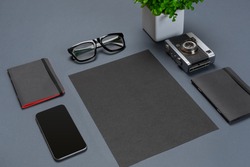 A set of black office accessories, glasses, green flower and smart on gray background