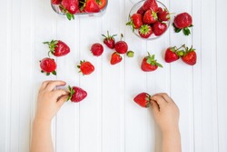 strawberry in the hand of a child on a white background