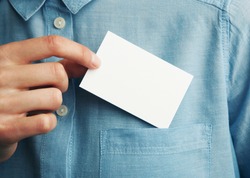 Young man who takes out blank business card from the pocket of his shirt