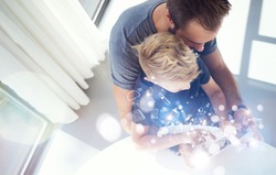 Dad and little boy playing together on mobile computer PC tablet, resting in modern house.Childhood dreams icons concept.Horizontal, blurred background. Top view