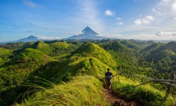 Hiker with backpack looks at the view on the Mayon volcano,Quit in Day Hills area,Philippines