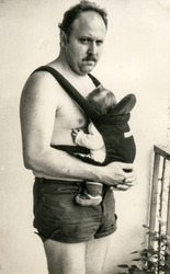 Vintage photo of father with baby daughter in baby carrier (1981)