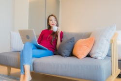Portrait beautiful young asian woman use laptop computer on sofa in living area at bedroom interior