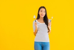Portrait beautiful young asian woman show spoon and fork ready to eat on yellow isolated background