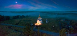 Eastern Europe, Ukraine, drone night photo of an illuminated temple against the backdrop of a foggy landscape near the city of Galich.