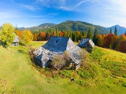 Houses of shepherds wooden old in the Carpathians, Ukraine, autumn beech and coniferous forest, beautiful ecological landscape. Aerial view drone copter